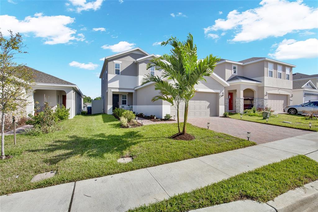A two-story suburban house with a paved driveway, a palm tree, and a grassy lawn — 1601 SWAN SWIM DRIVE, DAVENPORT, FL