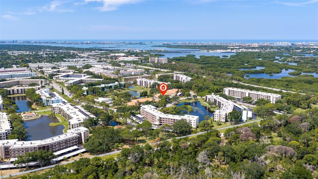 An aerial view shows multiple apartment buildings surrounded by lush greenery and several ponds — 8140 TERRACE GARDEN DRIVE UNIT 103, ST PETERSBURG, FL