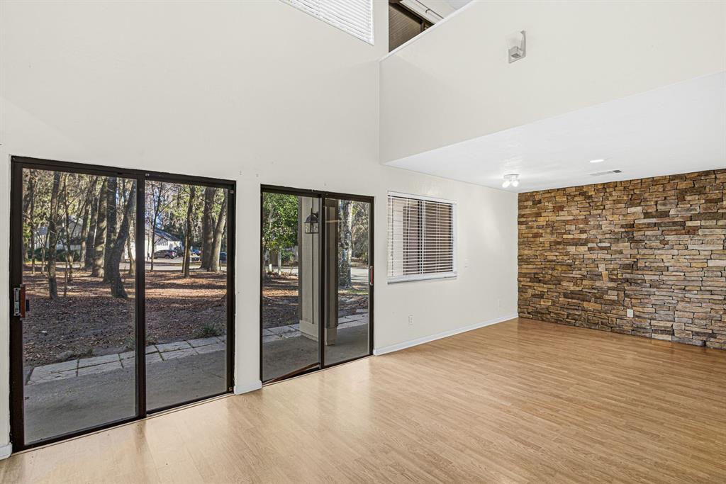 A living room features light wood flooring, a stone accent wall, and sliding glass doors — 5528 SW 4TH PLACE UNIT 5528, GAINESVILLE, FL