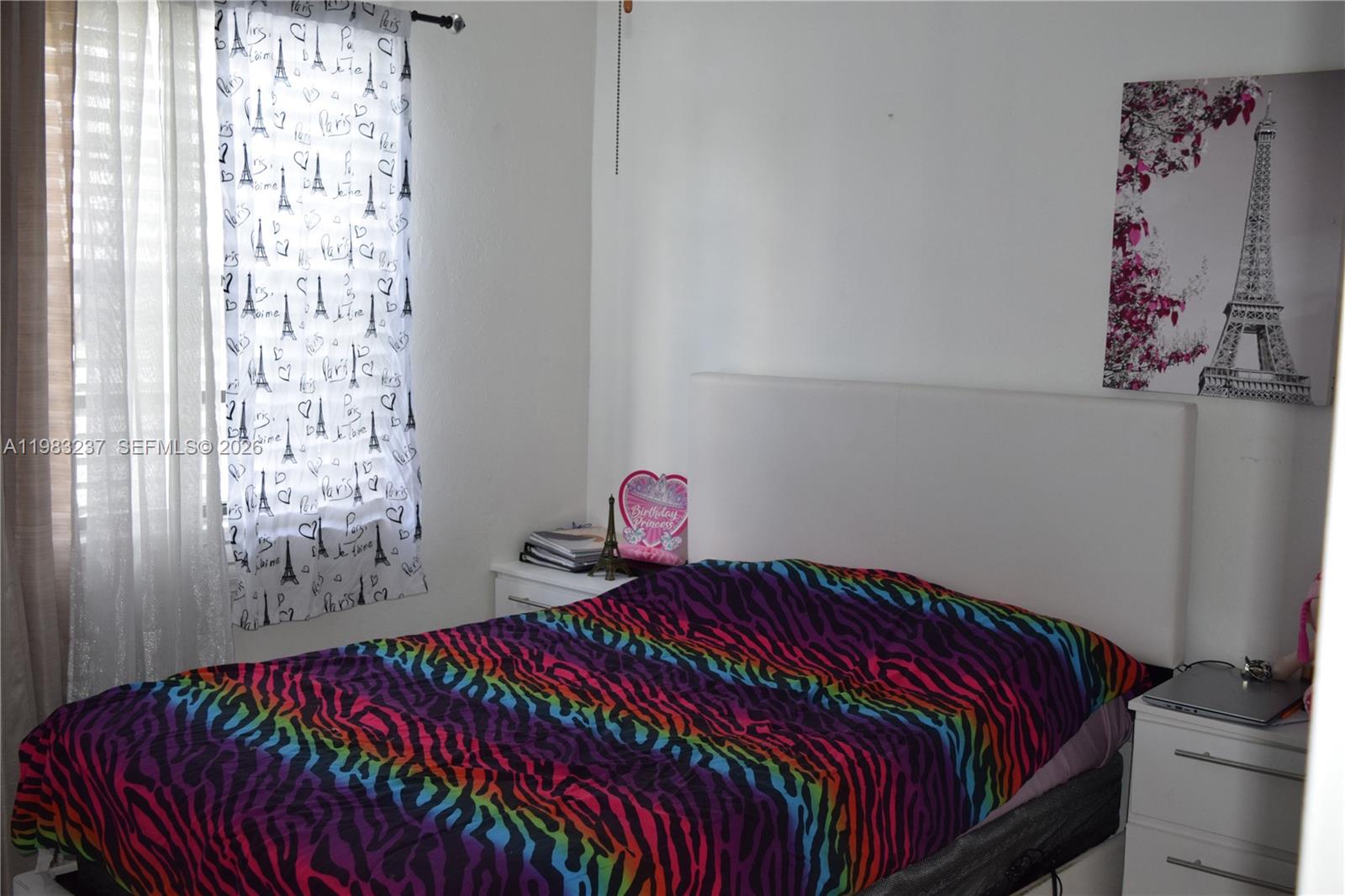 A bedroom features a bed with a colorful zebra-print comforter and Paris-themed decor — 1335 W 68th St # 106, Hialeah FL 33014, HIALEAH, FL