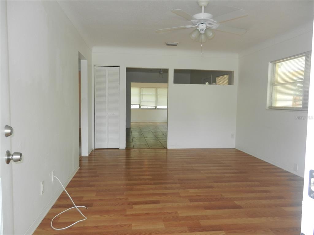 An interior view of a living room with wood-look flooring, white walls, and a ceiling fan — 5744 2ND AVENUE N, ST PETERSBURG, FL