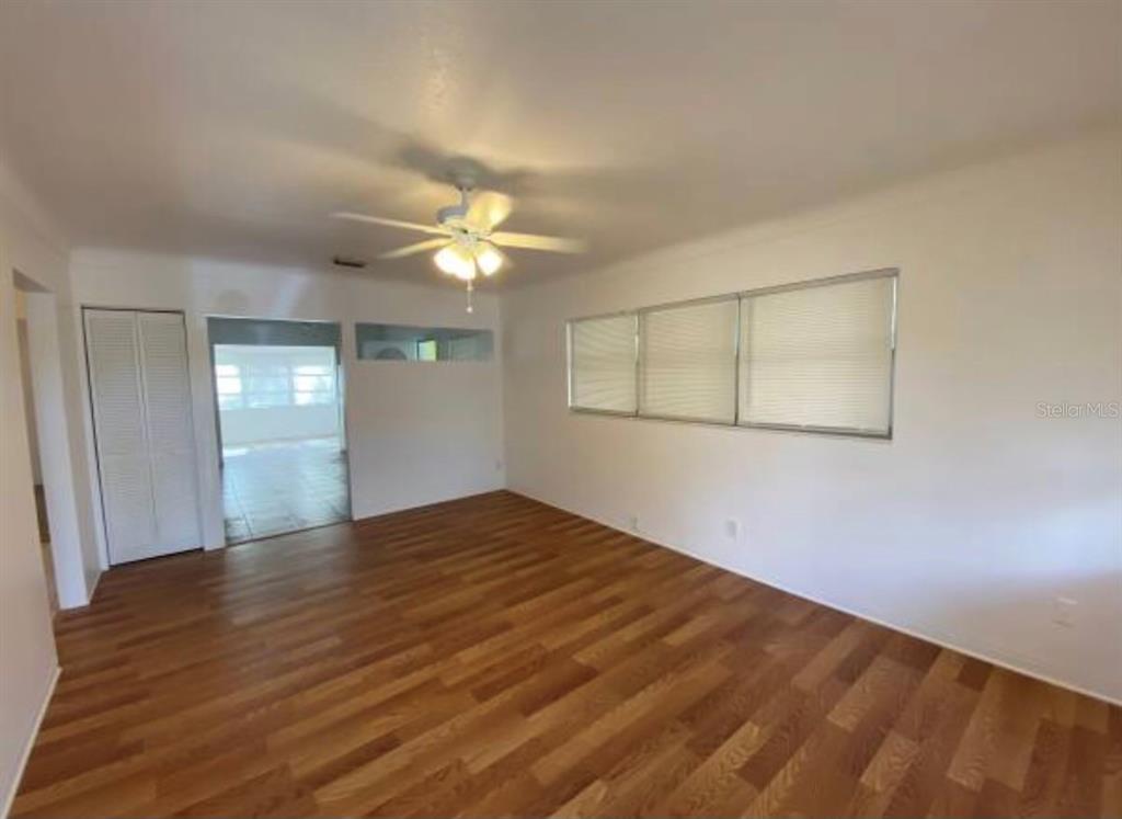 An empty room features wood-look flooring, white walls, a ceiling fan, and a window — 5744 2ND AVENUE N, ST PETERSBURG, FL