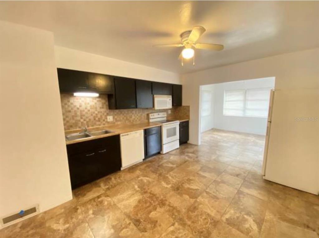 A kitchen features dark cabinets, a tiled backsplash, light countertops, and tile flooring — 5744 2ND AVENUE N, ST PETERSBURG, FL