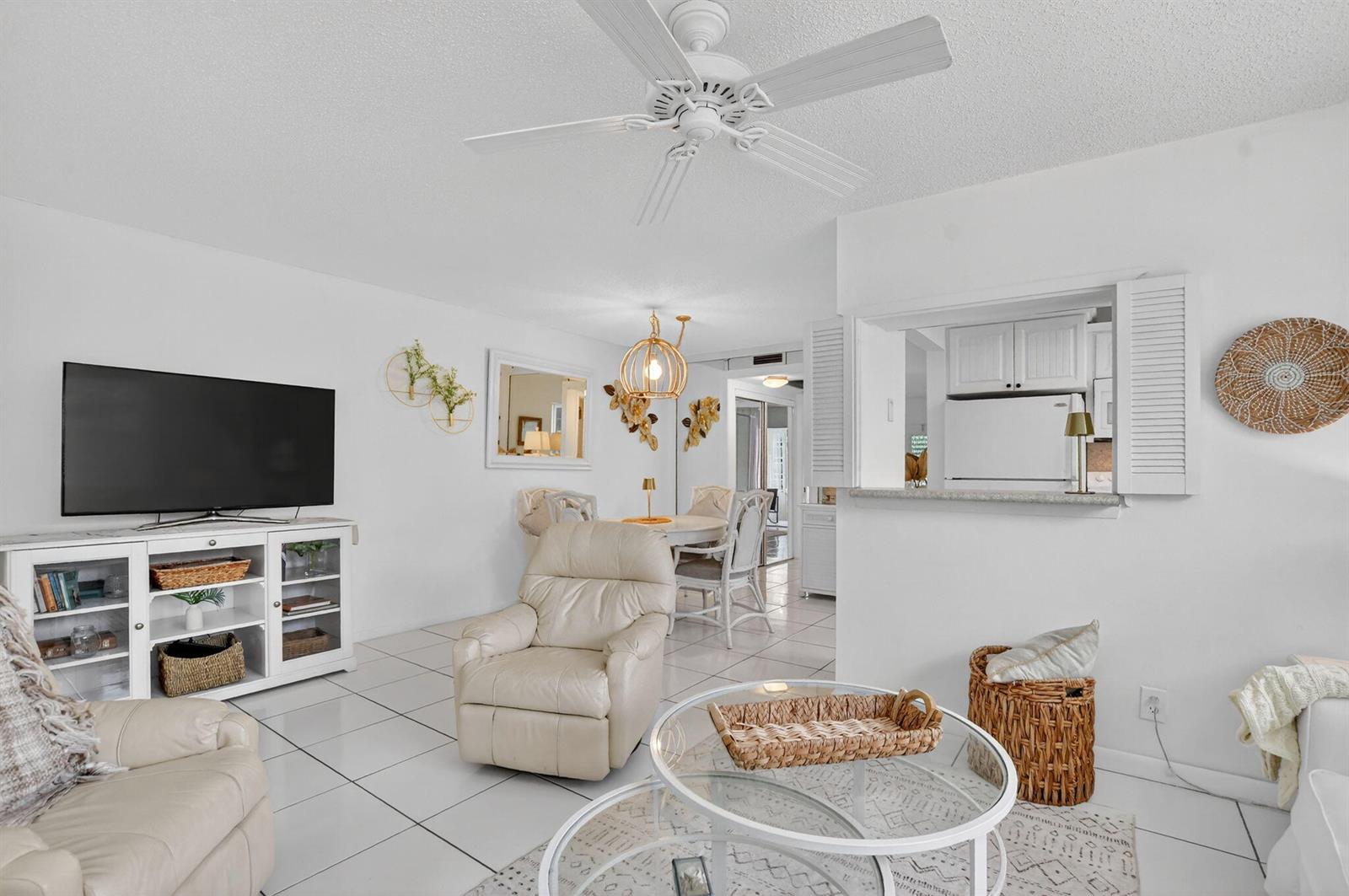 A bright living and dining area features white tile floors, a ceiling fan, and furniture — 477 Tilford V, Deerfield Beach FL 33442, DEERFIELD BEACH, FL