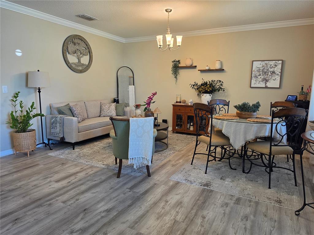 A living and dining area features light-colored walls, wood-look flooring, and a chandelier — 1762 BROCKRIDGE ROAD, KISSIMMEE, FL