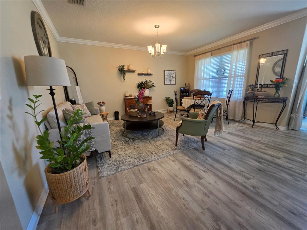 A living and dining area features light-colored walls, wood-look flooring, and a round coffee table — 1762 BROCKRIDGE ROAD, KISSIMMEE, FL