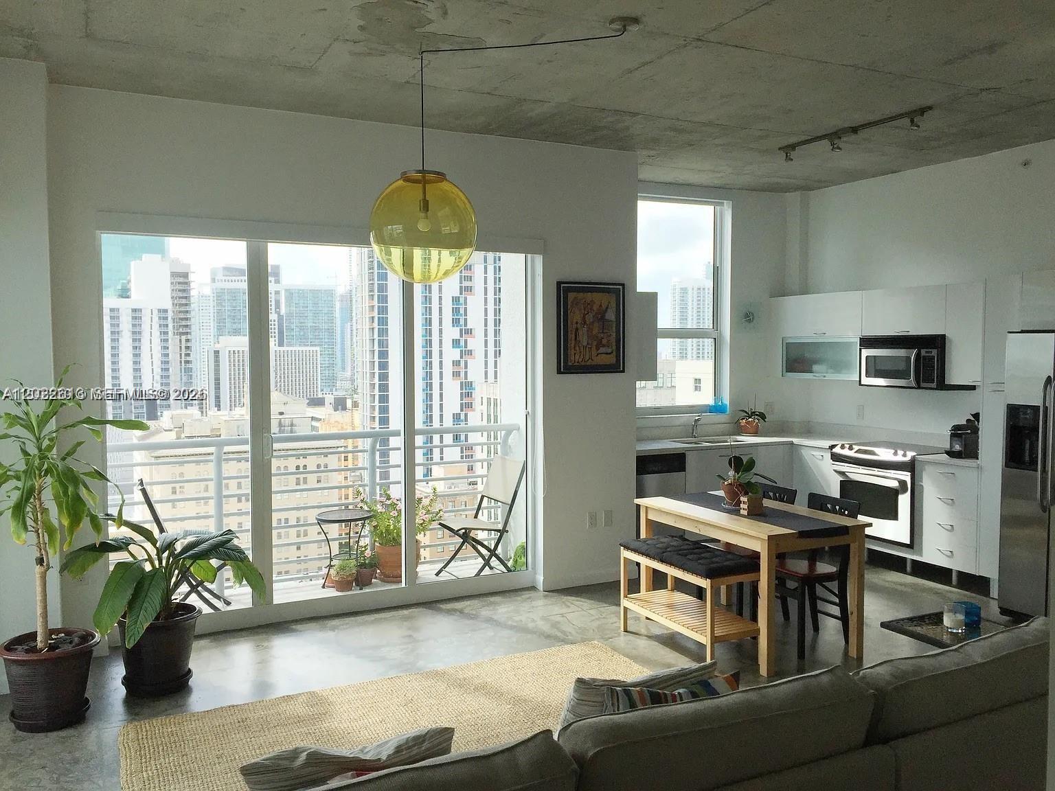 A modern apartment living area features a kitchen, dining table, and balcony with city views — 133 NE 2nd Ave # 2302, Miami FL 33132, MIAMI, FL
