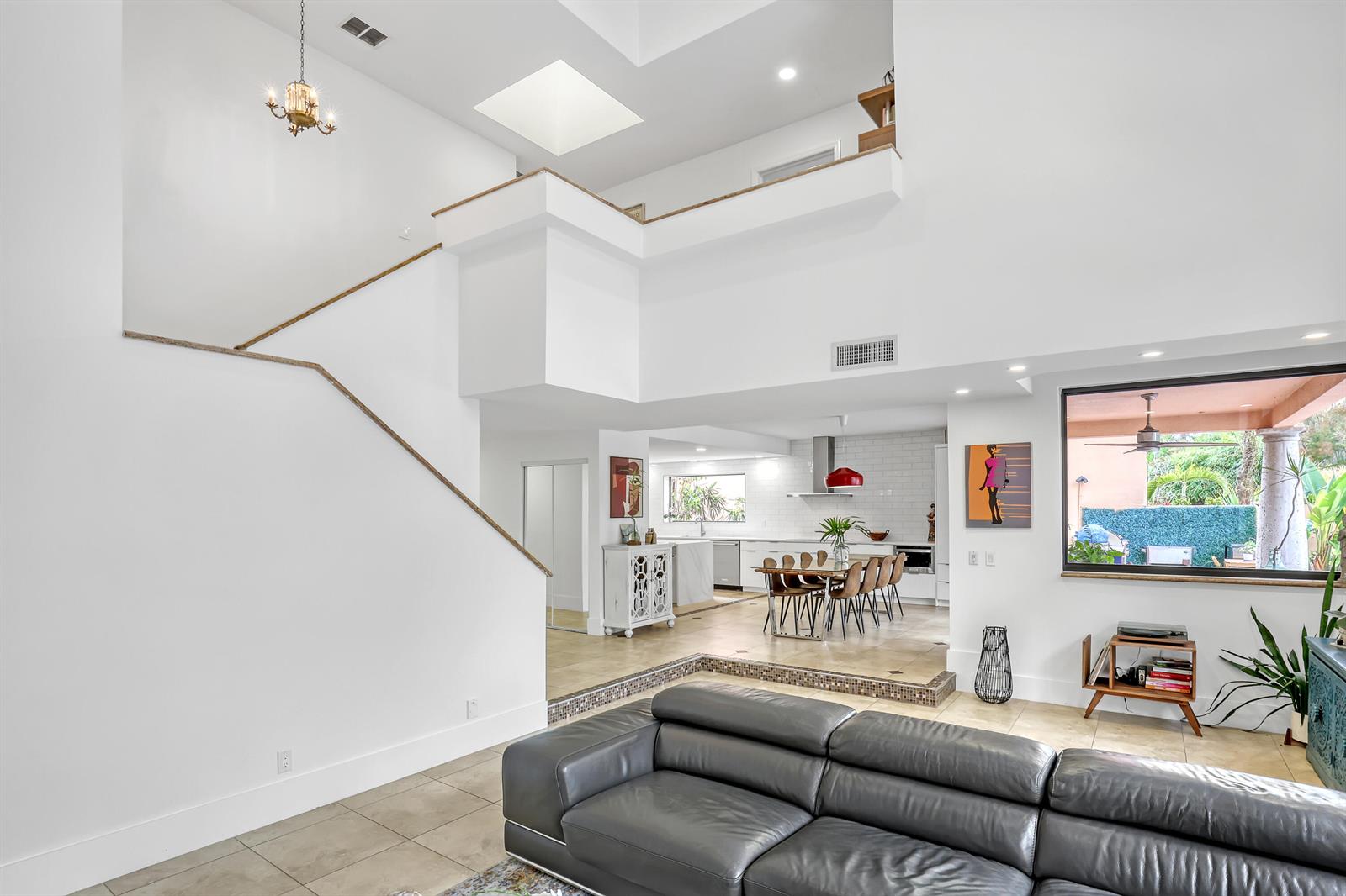 A living room with a sunken floor, leather sofa, and an open view into the kitchen — 6532 Via Rosa, Boca Raton FL 33433, BOCA RATON, FL