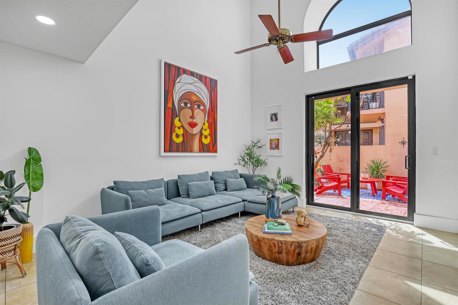 A living room with a blue sectional, wood coffee table, and sliding doors to a patio — 6532 Via Rosa, Boca Raton FL 33433, BOCA RATON, FL