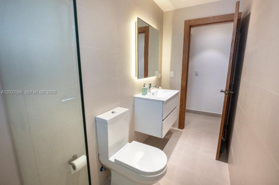A modern bathroom features a floating vanity, a wall-mounted mirror, and a glass-enclosed shower — 0 El hicoteco # 0, FL