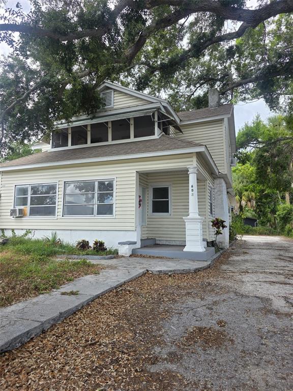 A two-story house with light yellow siding, a front porch, and a large oak tree — 602 W 26TH STREET, BRADENTON, FL