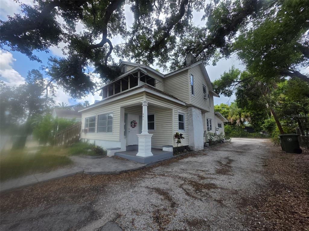 A two-story house with light yellow siding, a front porch, and a gravel driveway — 602 W 26TH STREET, BRADENTON, FL