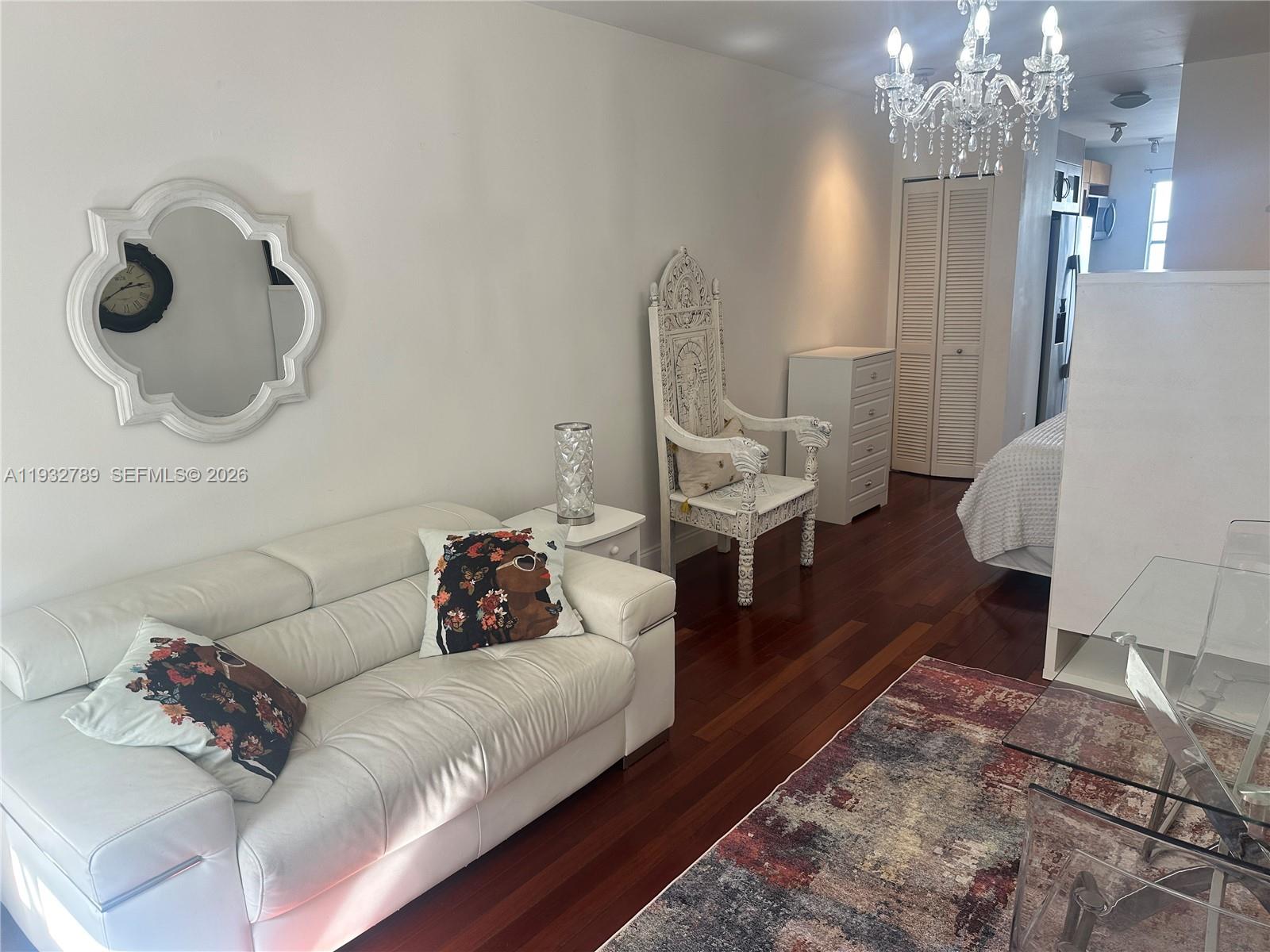 A living area features a white sofa, ornate chair, chandelier, and hardwood flooring — 1340 Drexel Ave # 406, Miami Beach FL 33139, MIAMI BEACH, FL