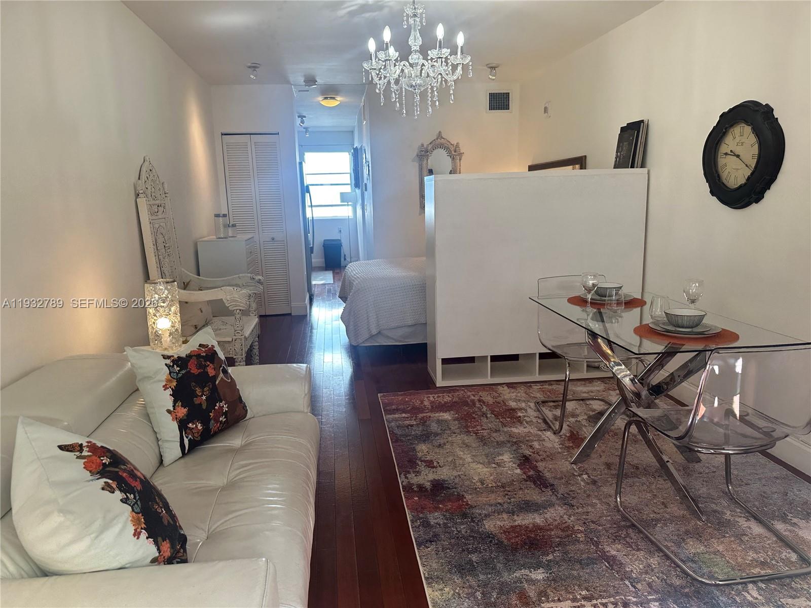 A studio apartment features a white sofa, a glass dining table, and a partitioned bed — 1340 Drexel Ave # 406, Miami Beach FL 33139, MIAMI BEACH, FL