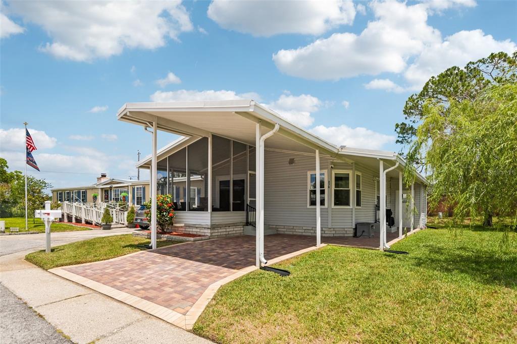 A single-story manufactured home with a paved carport and a screened-in front porch — 276 PELICAN DRIVE N, OLDSMAR, FL