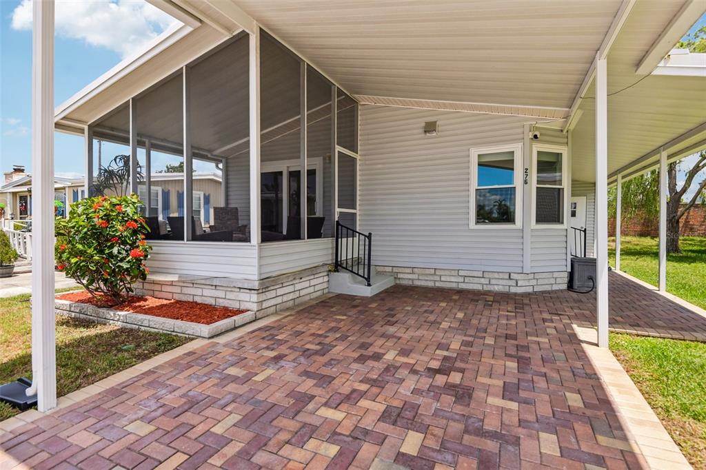 A paved driveway leads to a screened-in porch and a house with light gray siding — 276 PELICAN DRIVE N, OLDSMAR, FL