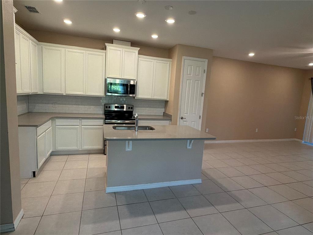 A kitchen with white cabinets, a central island, and tile flooring in an open space — 3497 FALLBROOK DRIVE, KISSIMMEE, FL