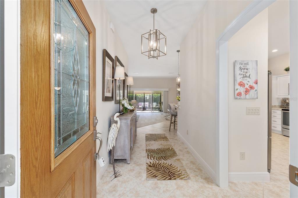 A bright entryway with tile flooring leads toward a living area and kitchen — 1440 ALESIO STREET, THE VILLAGES, FL
