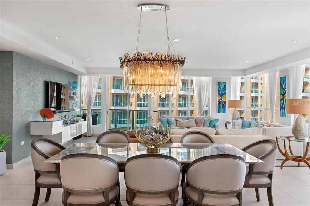 A dining area with a glass table and chandelier opens to a living room with balconies — 25 MUÑOZ RIVERA AVE UNIT 614, SAN JUAN, PR