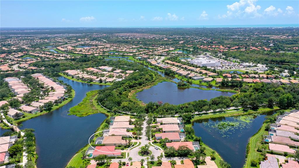 An aerial view shows a residential neighborhood with houses surrounding several interconnected lakes — 8672 DOLCE LANE, SARASOTA, FL