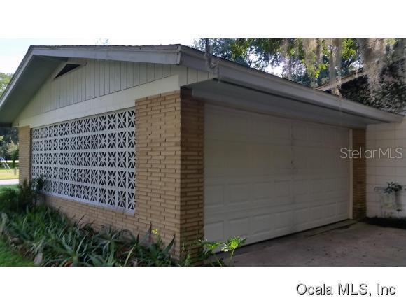 A side view of a house exterior featuring a garage door and decorative concrete blocks — 908 SE 23 STREET, OCALA, FL