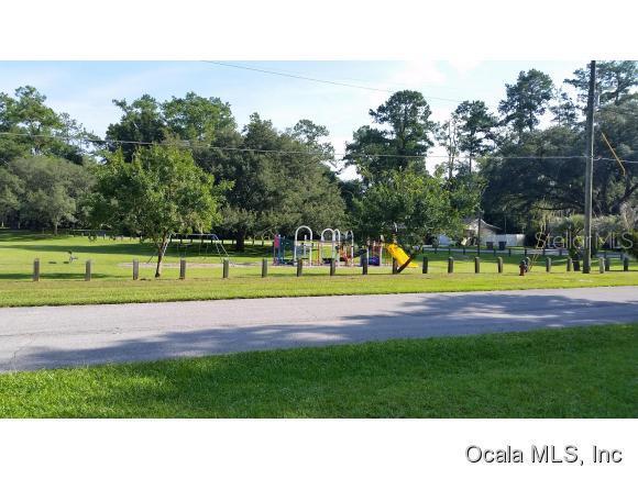 A playground with a slide and swings sits in a grassy park near a road — 908 SE 23 STREET, OCALA, FL