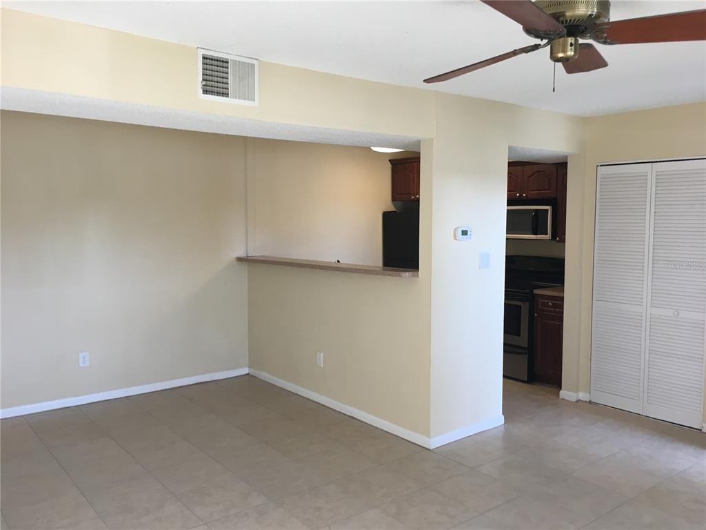 An open-concept living area features a breakfast bar, tiled floors, and an adjacent kitchen — 455 ALT 19 S UNIT 141, PALM HARBOR, FL