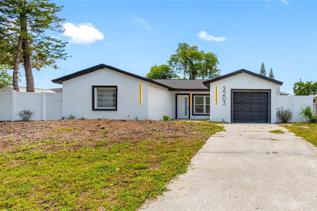 A single-story white house with a dark garage door and a concrete driveway — 3203 RIVER COVE DRIVE, TAMPA, FL