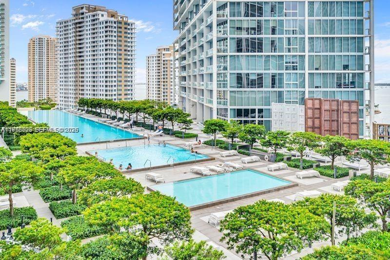 An elevated view shows three swimming pools surrounded by trees and lounge chairs near skyscrapers — 485 Brickell Ave # 1711, Miami FL 33131, MIAMI, FL