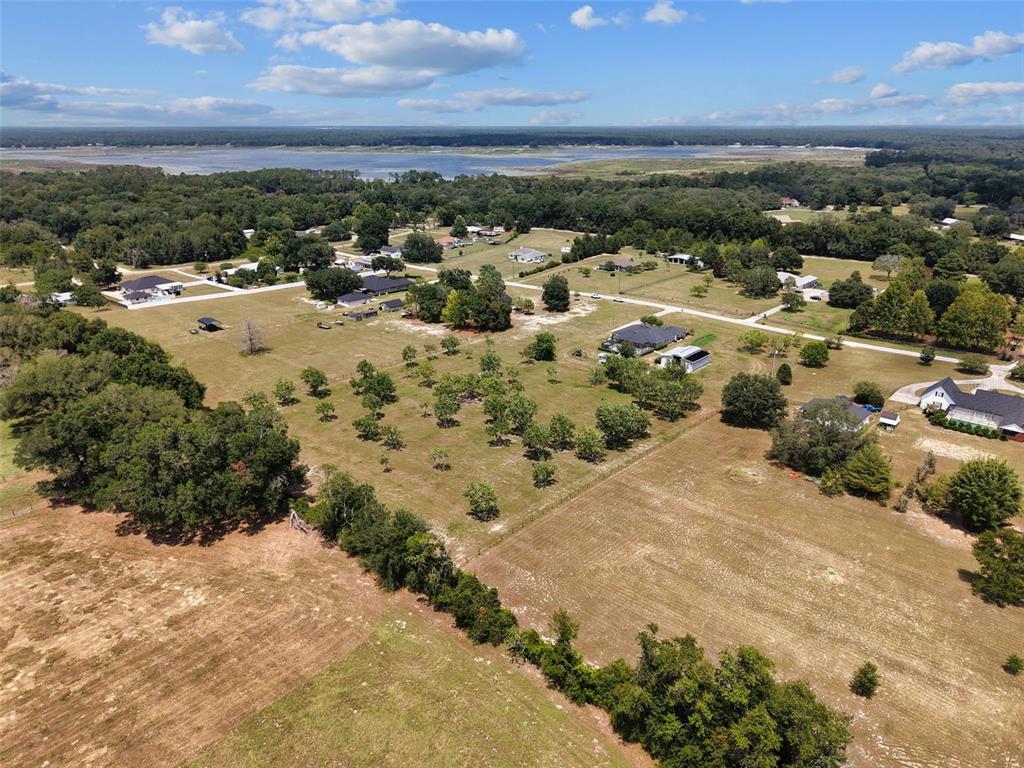 An aerial view shows a rural landscape with scattered houses, trees, and a distant lake — 8140 MEADOWLARK CT, MELROSE, FL