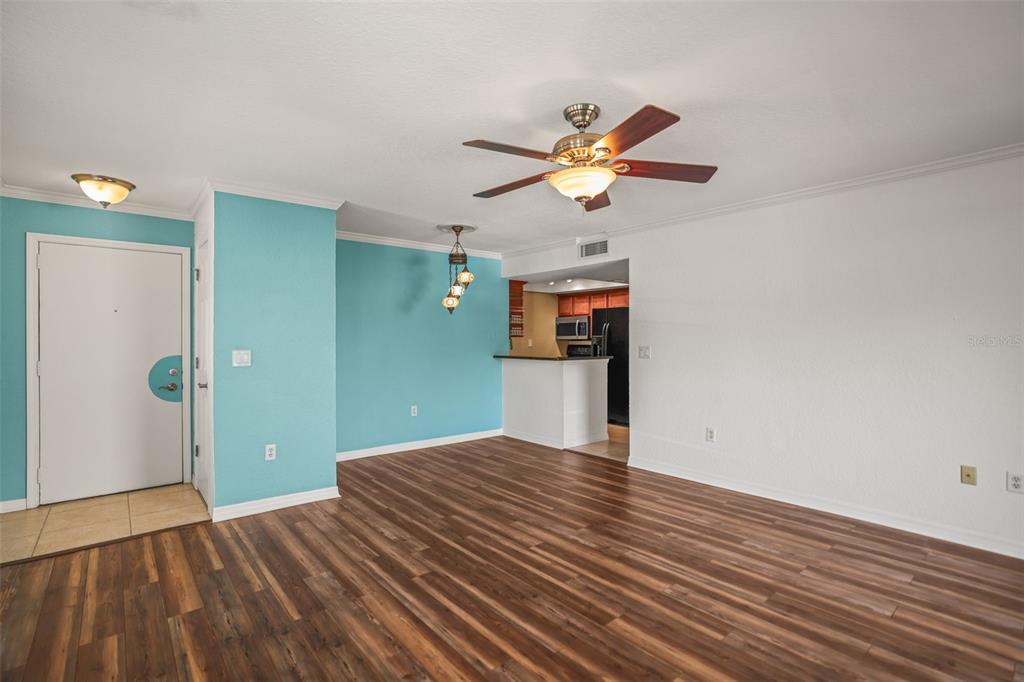 An open-concept living and dining area features wood-look flooring, teal accent walls, and a ceiling fan — 704 LYNDHURST STREET UNIT 624, DUNEDIN, FL
