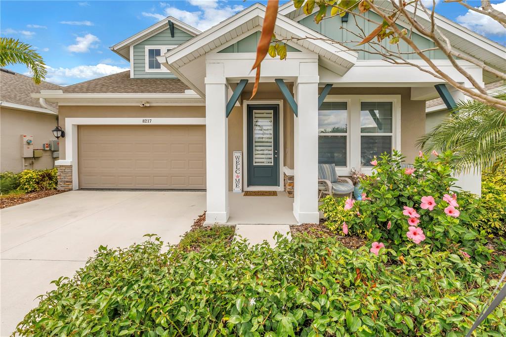 A single-story house with a tan garage, blue front door, and a landscaped front yard — 8217 TRIMBELLE, PARRISH, FL