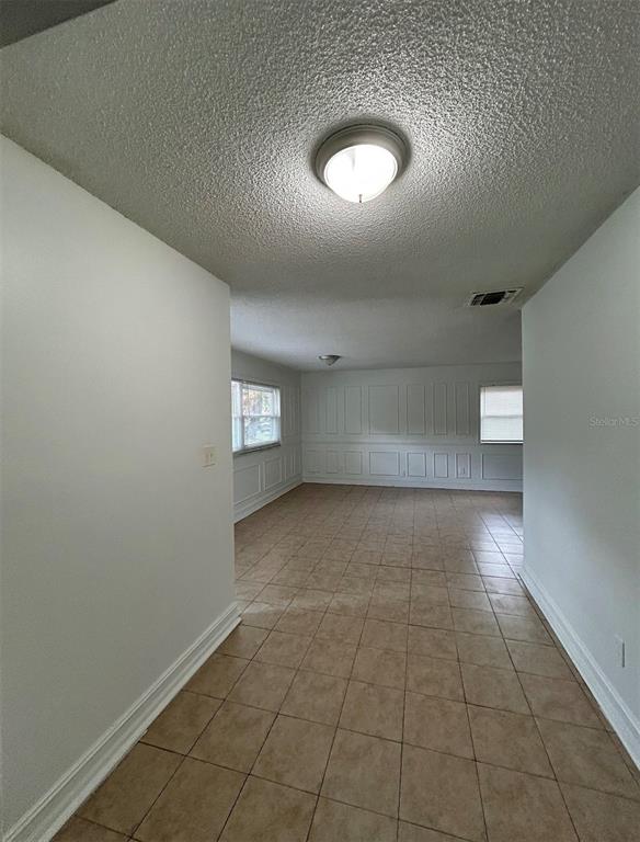 A hallway with tile flooring leads into a living area featuring white wainscoting — 625 19TH STREET, ORLANDO, FL