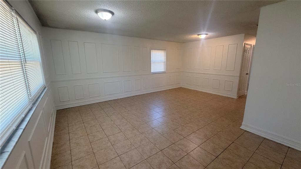 An empty room features white wainscoting, tiled flooring, and two flush-mount ceiling lights — 625 19TH STREET, ORLANDO, FL