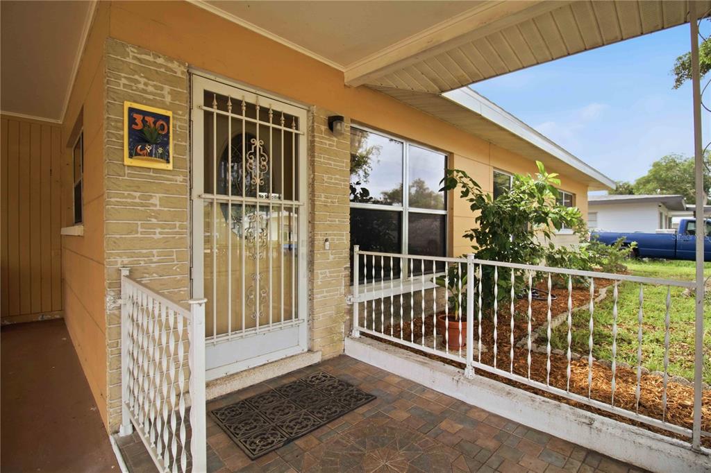 A covered front porch with a security door, stone-textured siding, and a white metal railing — 330 CROSBY COURT, SARASOTA, FL
