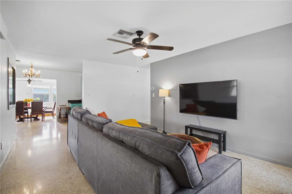 A living room features a grey sectional sofa, a wall-mounted television, and terrazzo flooring — 330 CROSBY COURT, SARASOTA, FL