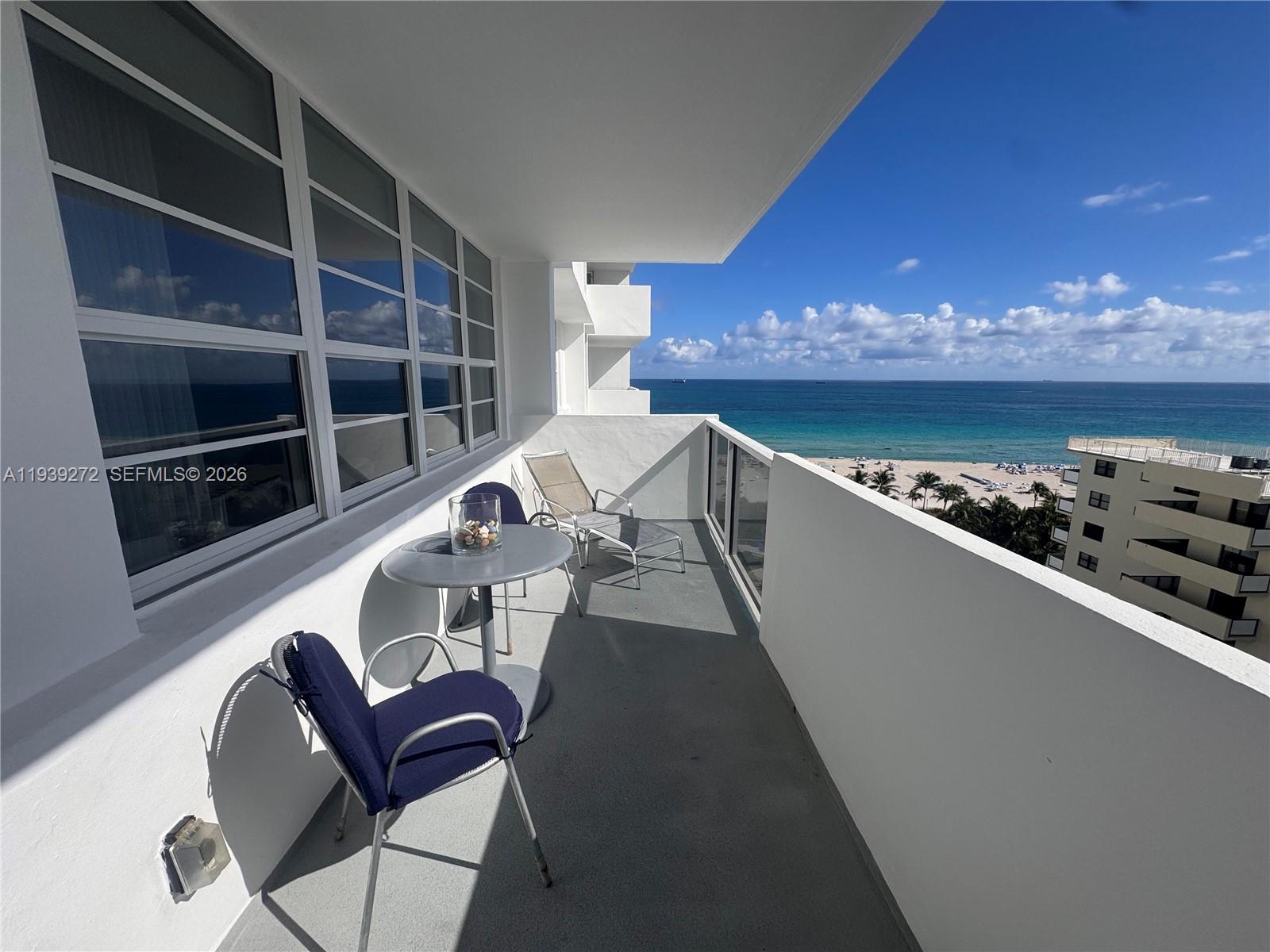 A balcony with a table, chairs, and a view of the ocean and beach — 100 Lincoln Rd # 1230, Miami Beach FL 33139, MIAMI BEACH, FL