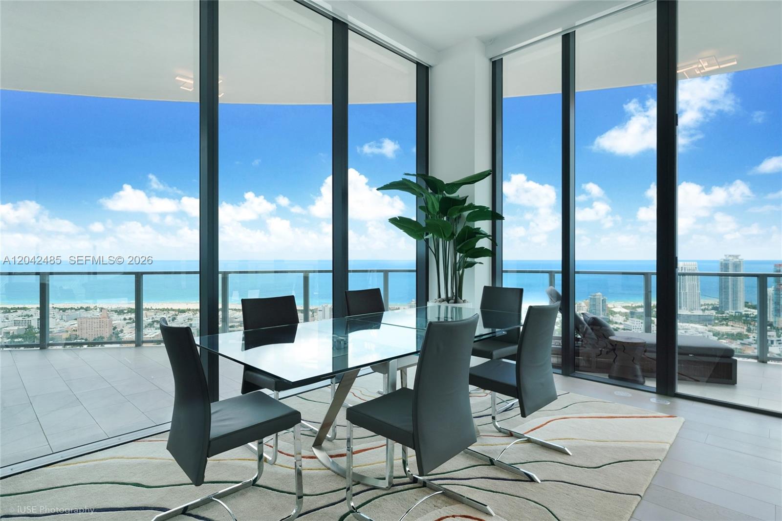 A dining area features a glass table, six chairs, and floor-to-ceiling windows overlooking the ocean — 500 Alton Rd # 4401, Miami Beach FL 33139, MIAMI BEACH, FL