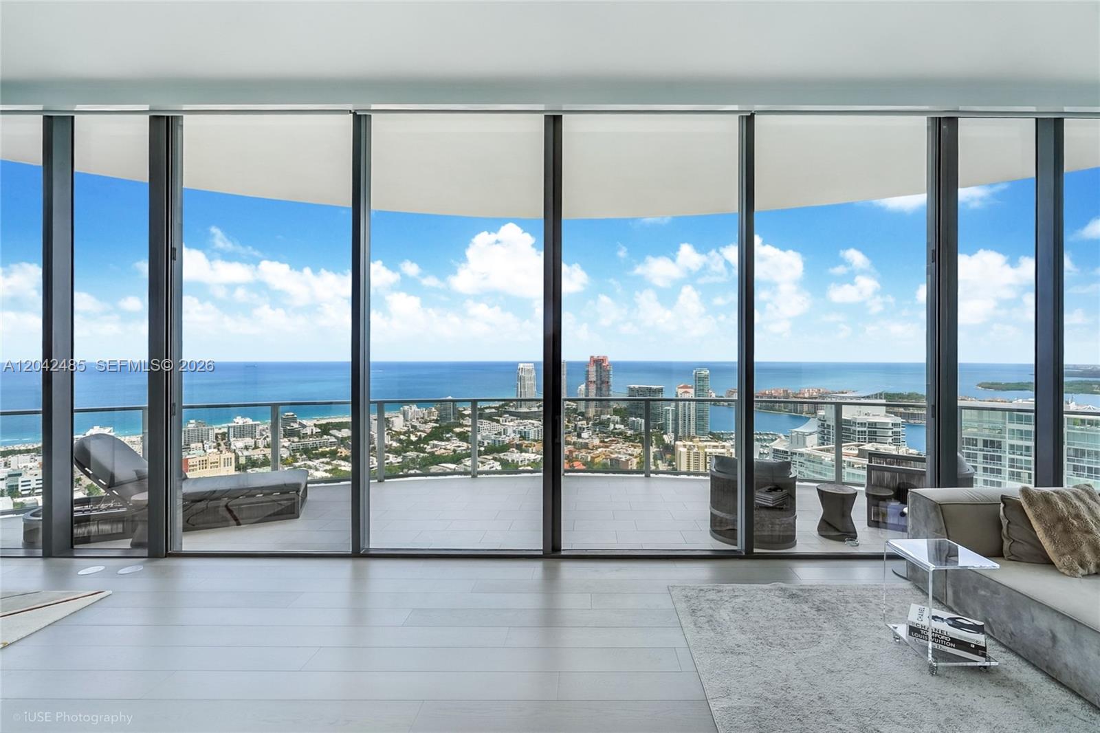 A modern living room features floor-to-ceiling windows overlooking a balcony, city skyline, and ocean — 500 Alton Rd # 4401, Miami Beach FL 33139, MIAMI BEACH, FL