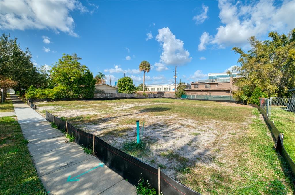 A vacant, fenced-in residential lot sits next to a sidewalk under a blue sky — 307 E HARVARD STREET, ORLANDO, FL