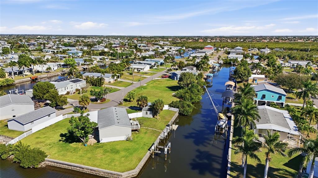 An aerial view shows houses along a canal with a boat docked near palm trees — 751 CORAL DRIVE, PUNTA GORDA, FL
