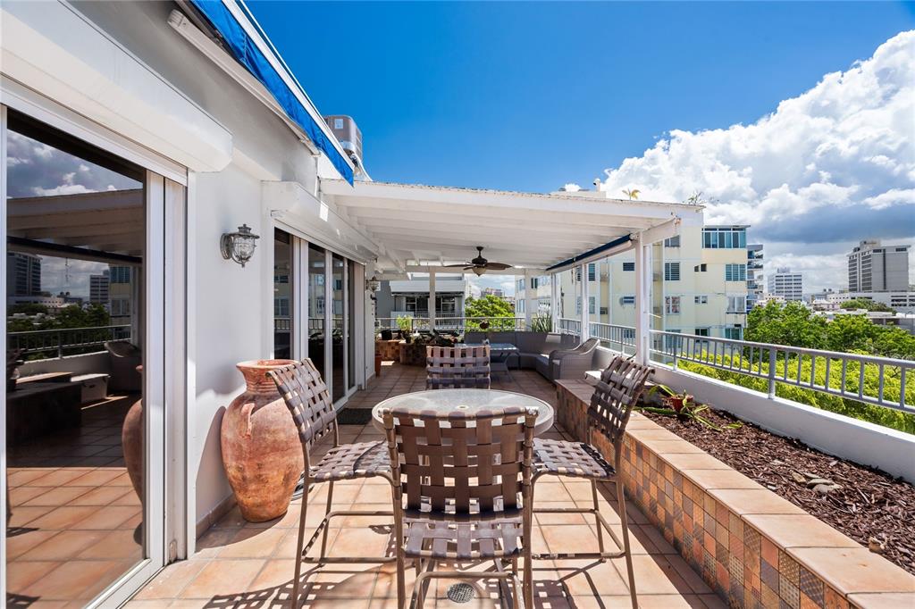 A spacious outdoor terrace features a covered patio, dining set, and views of city buildings — 85 CALLE CARIBE UNIT PH 601, SAN JUAN, PR