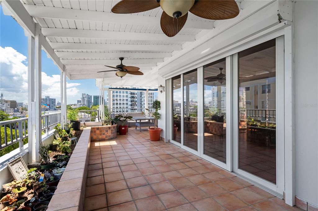 A covered balcony features tiled flooring, potted plants, ceiling fans, and large sliding glass doors — 85 CALLE CARIBE UNIT PH 601, SAN JUAN, PR