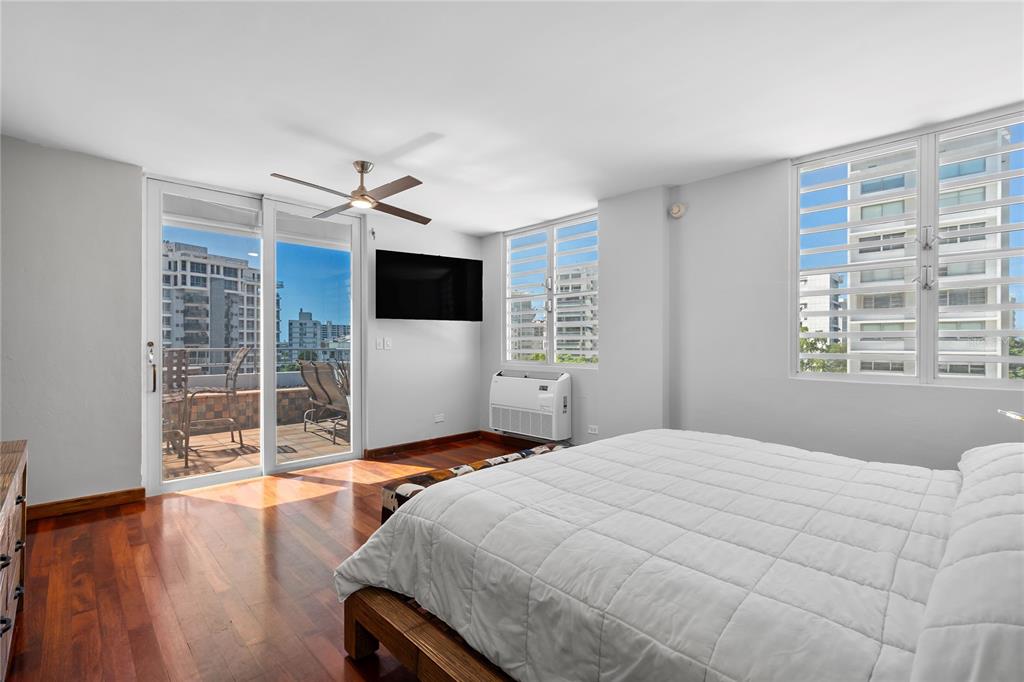 A bedroom with hardwood floors, a white bed, a ceiling fan, and a balcony door — 85 CALLE CARIBE UNIT PH 601, SAN JUAN, PR