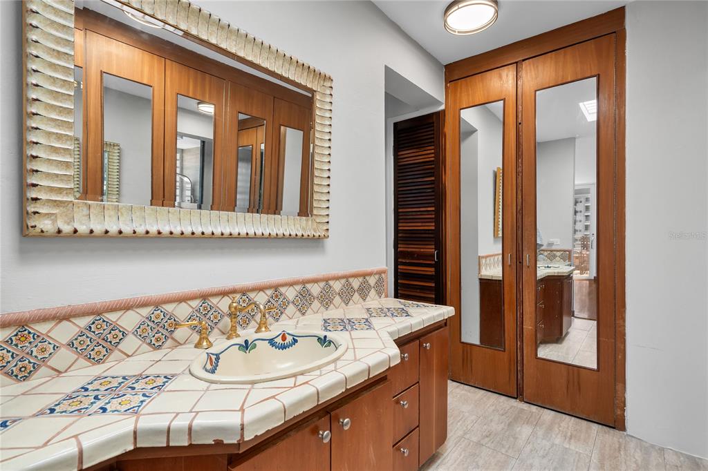 A bathroom features a tiled vanity with a decorative sink, wood cabinetry, and mirrored doors — 85 CALLE CARIBE UNIT PH 601, SAN JUAN, PR