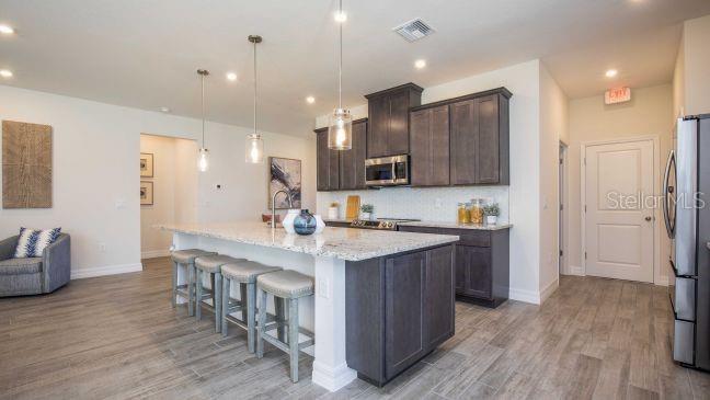 A modern kitchen features dark wood cabinets, granite countertops, a large island, and wood-look flooring — TBD NANTUCKET TERRACE, NORTH PORT, FL