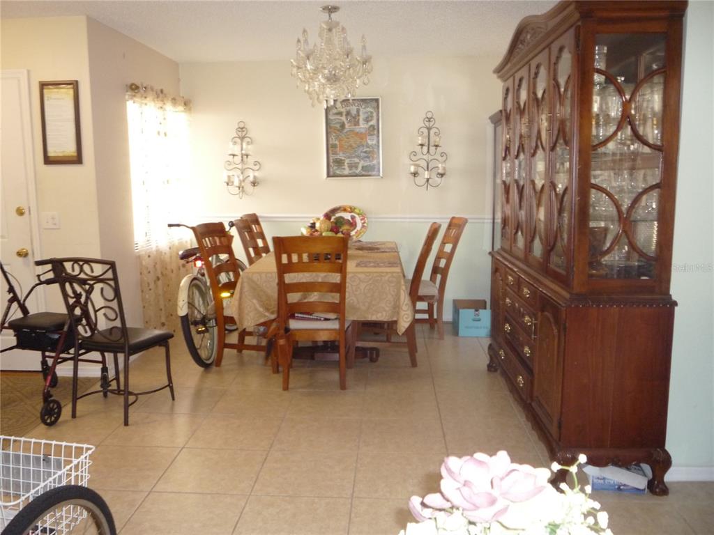 A dining room features a wooden table with chairs, a large china cabinet, and tile flooring — 101 GRAND PLAZA DRIVE UNIT F3, ORANGE CITY, FL