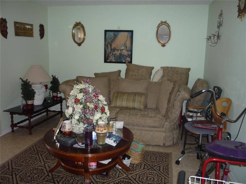 A living room features a beige sofa, a round wooden coffee table, and wall decor — 101 GRAND PLAZA DRIVE UNIT F3, ORANGE CITY, FL
