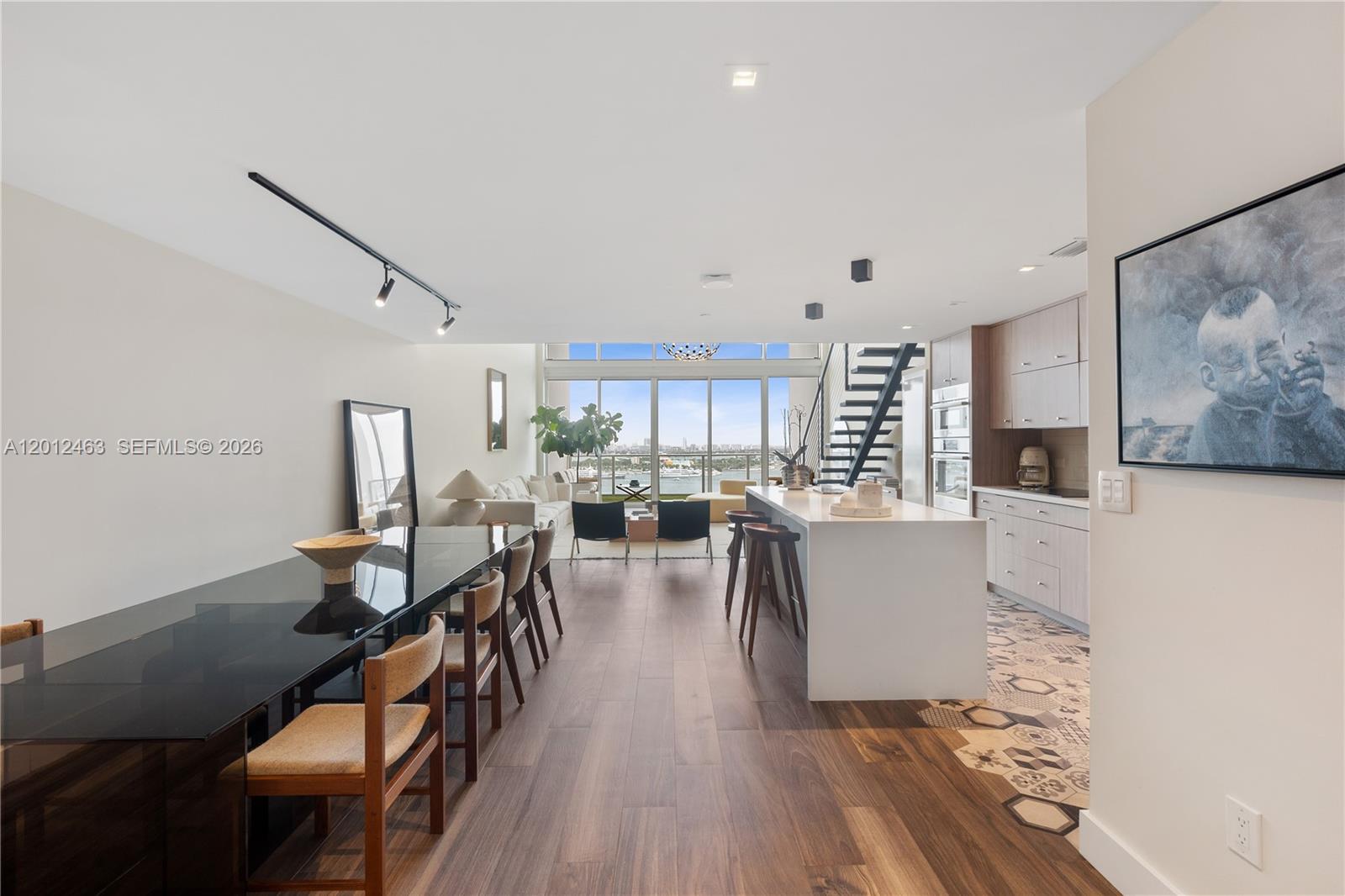 A modern open-concept living area features a dining table, kitchen island, and floor-to-ceiling windows — 1040 Biscayne Blvd # 1602, Miami FL 33132, MIAMI, FL