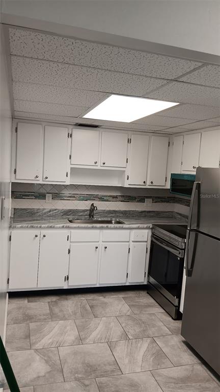 A kitchen with white cabinets, gray countertops, stainless steel appliances, and tiled flooring — 8402 111TH STREET UNIT 203, SEMINOLE, FL